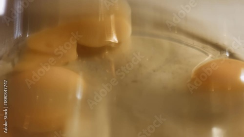 Cracked eggs in a glass bowl, macro view