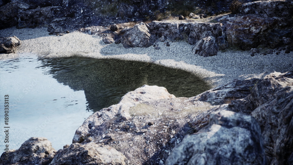 Naklejka premium Soft waters reflect the evening sky as rocky formations surround a quiet cove. The shoreline is dotted with smooth pebbles, creating a natural retreat for contemplation.