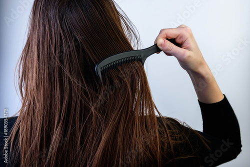 Cuadro en lienzo Young woman combing dirty oily hair on gray background.