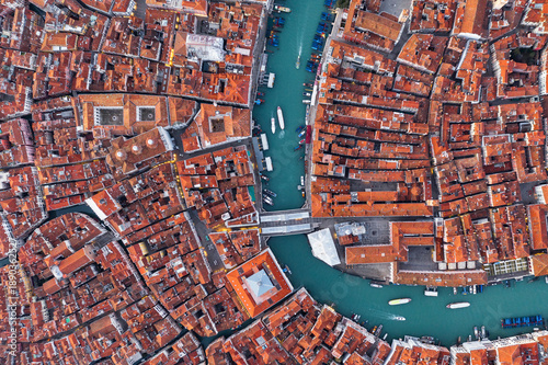 Aerial view of terracotta rooftops cascading around winding turquoise canals, a maze of history and beauty, Venice, Veneto, Italy.