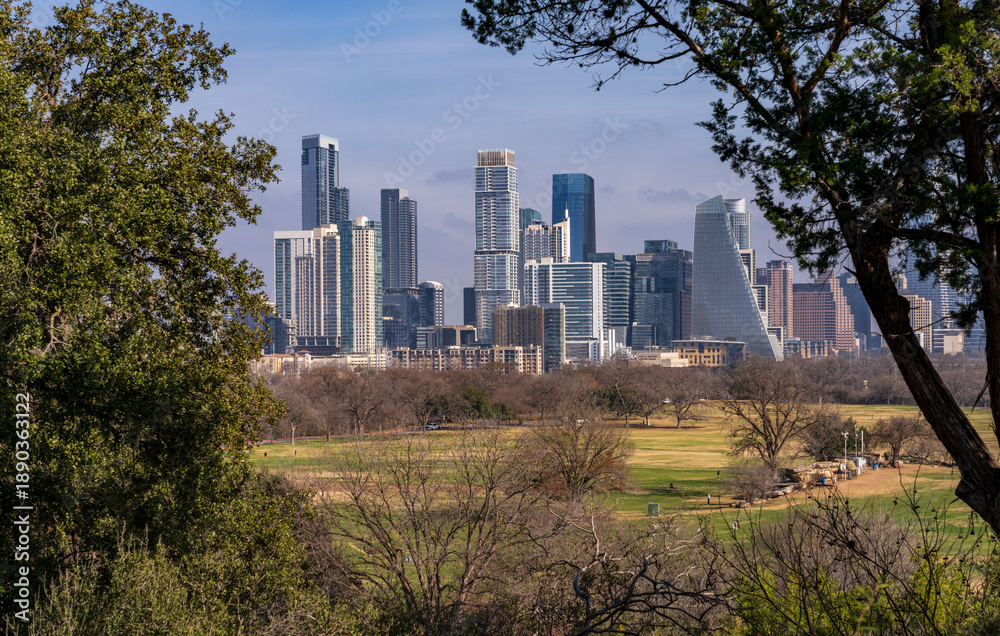 Fototapeta premium Framed view of Austin Texas city skyline through the trees of Zilker Botanic Gardens and park outside the city