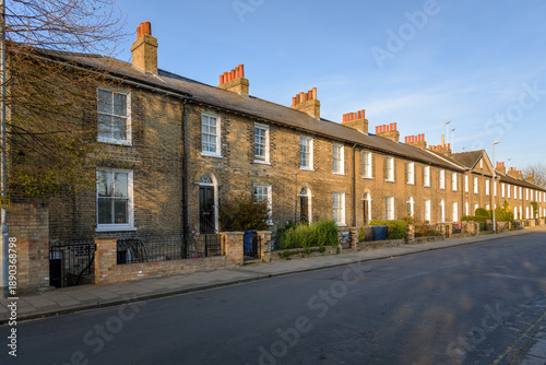 Traditional brick trerraced houses with fenced front gardens and strairs to the front doors along a street in a city centre at sunset in spring