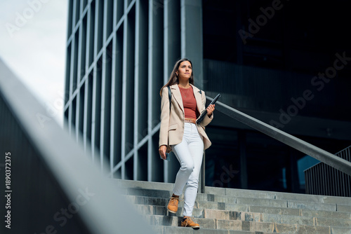Elegant young businesswoman going down the street stairs.