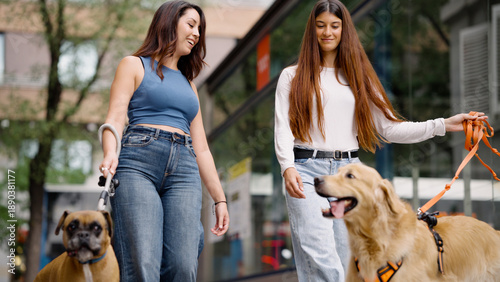 Photography Two young women friends walking their dogs on leashes in an urban environment, e
