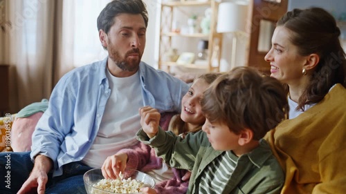Kids hands taking popcorn feeding father enjoying comedy show television closeup