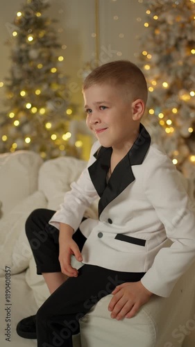 Wallpaper Mural Smiling boy in a stylish suit sitting on the sofa. New Year celebration concept. Torontodigital.ca