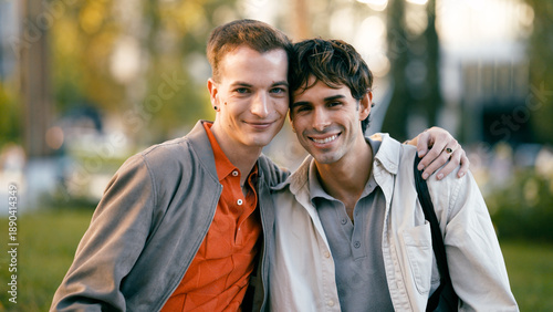 Two happy men embracing, enjoying a moment together in an outdoor park setting, expressing companionship and love