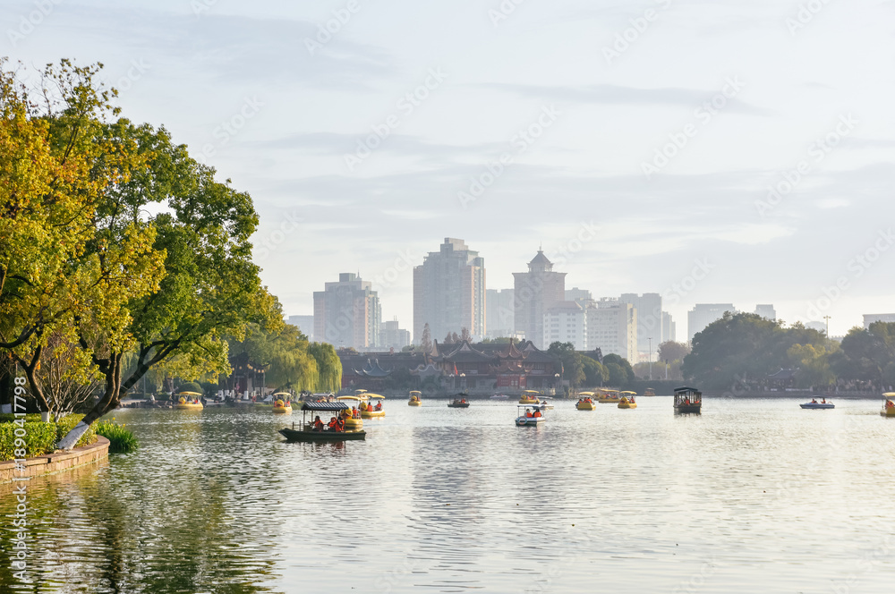 Fototapeta premium Winter landscape of leisure boats on the lake and city skyline in Moon Lake Park (Yuehu Park), Ningbo, China
