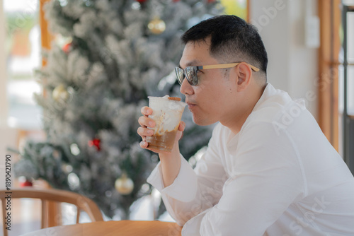 Happy man in a cafe drinking coffee looking away at coffee shop.