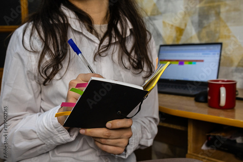 Fotografie Woman writing in a planner at her home office desk
