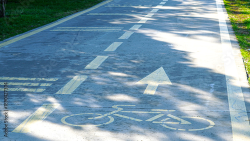 Foto Bicycle lane markings on concrete path in park with green grass nearby