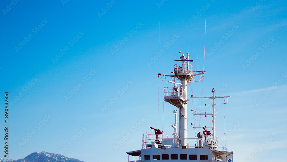 Fototapeta premium Ship navigation tower against clear blue sky with distant mountains visible