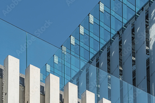 Bilde på lerret Modern glass facade with concrete columns and clear blue sky in the background
