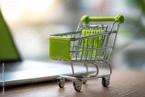 Green Mini Shopping Cart Beside Laptop on Wooden Desk: Modern Online Shopping Concept for Ecommerce, Retail, and Digital Marketplace Visualization