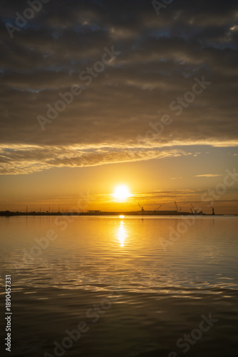 Golden Sunset over Industrial Harbor with Calm Water Reflections
