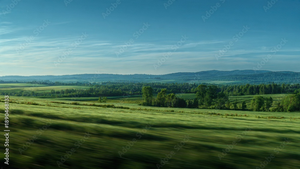 Obraz premium Green fields and distant hills under blue sky