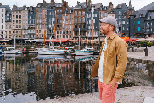 Φωτογραφία In the historic harbor of Honfleur, a man in a flat cap and yellow shirt gazes a