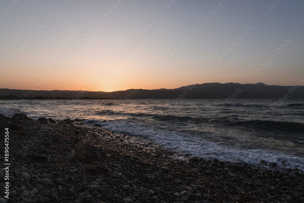 Obraz premium Sea panorama at sunset with waves washing over the stony beach shore