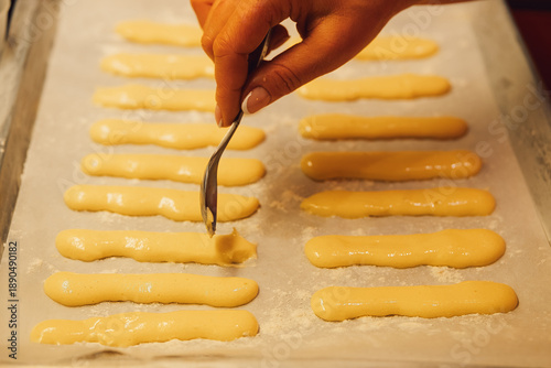 Photos Raw dough for savoyardi cookies for making tiramisu cake lies on parchment paper
