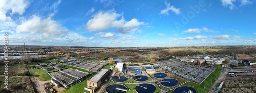Aerial view of circular tanks contrast against the green landscape under a sky streaked with white clouds, Hoddesdon, United Kingdom.