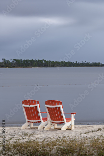 Two Red Chairs on a Serene, Cloudy Lakeshore