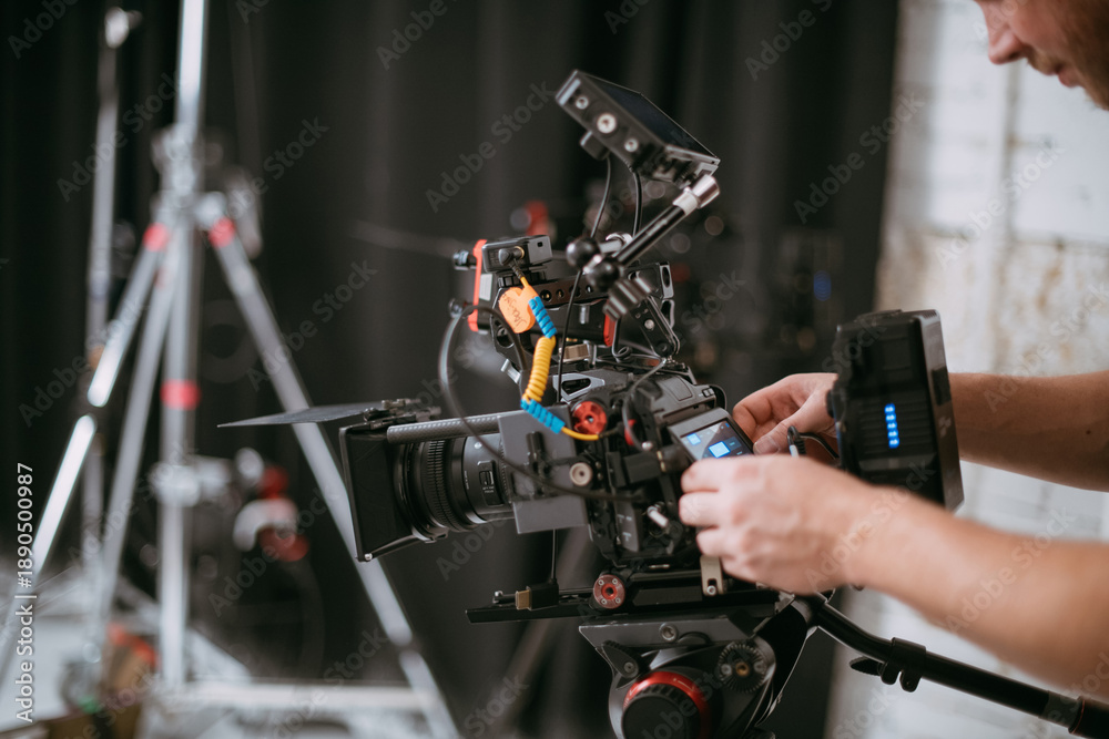 Fototapeta premium Professional cinema and video camera on the set. Shooting shift, lighting fixtures, shooting equipment and the team. Technique of modern filming and advertising.