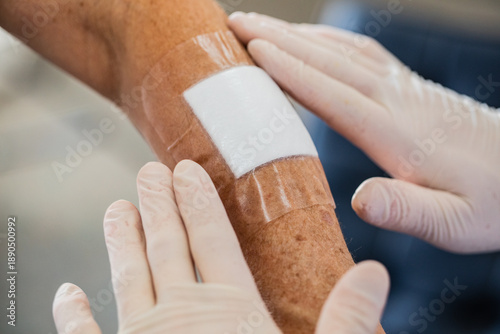 Konstfotografi A close up of nurses hands with gloves applying a hydrocolloid bandage onto an e