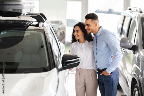 Φωτογραφία Happy middle-eastern young family choosing new auto in salon, standing by nice w