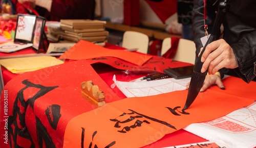 Bild auf Leinwand Close up of woman writing Happy New Year with Chinese calligraphy on couplets for celebration