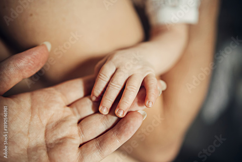 A baby's hand is being held by a woman's hand