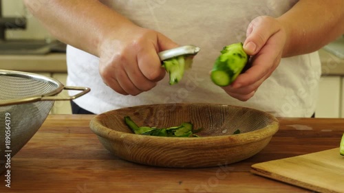 Woman cutting fresh cucumber for salad
