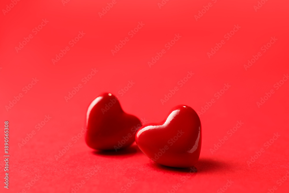 Fototapeta premium Love. Two decorative hearts on red background, closeup. Space for text