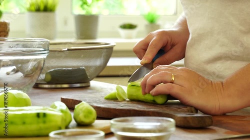 Woman cutting fresh cucumber for salad
