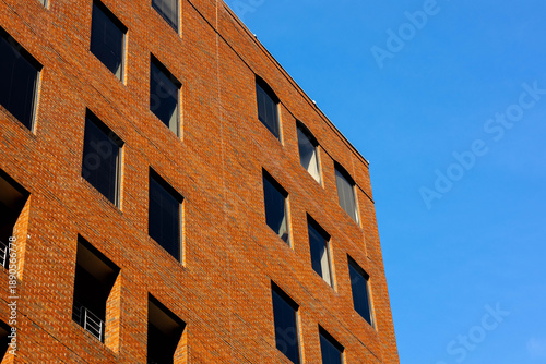 Bild auf Leinwand Modern Red Brick Office Building Exterior under Clear Blue Sky