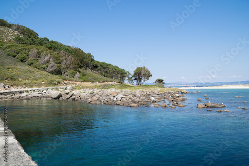 Natural coastal bay with turquoise water, sandy beach and forested hills