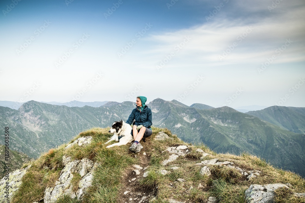 Fototapeta premium woman trekking with a dog in high mountains