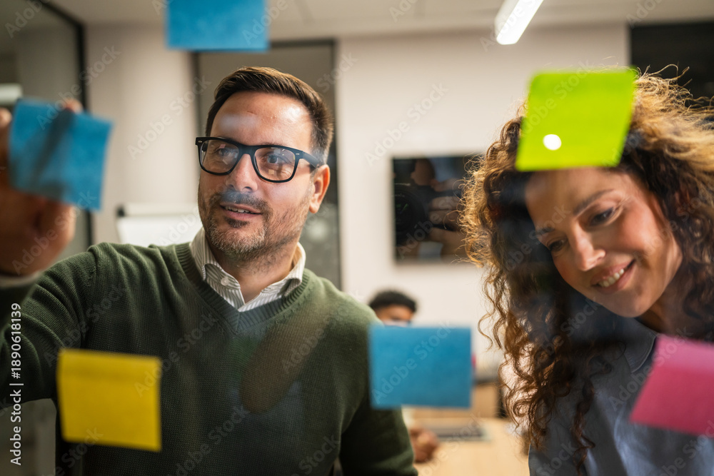Fototapeta premium Diverse business team collaborating planning ideas on glass wall