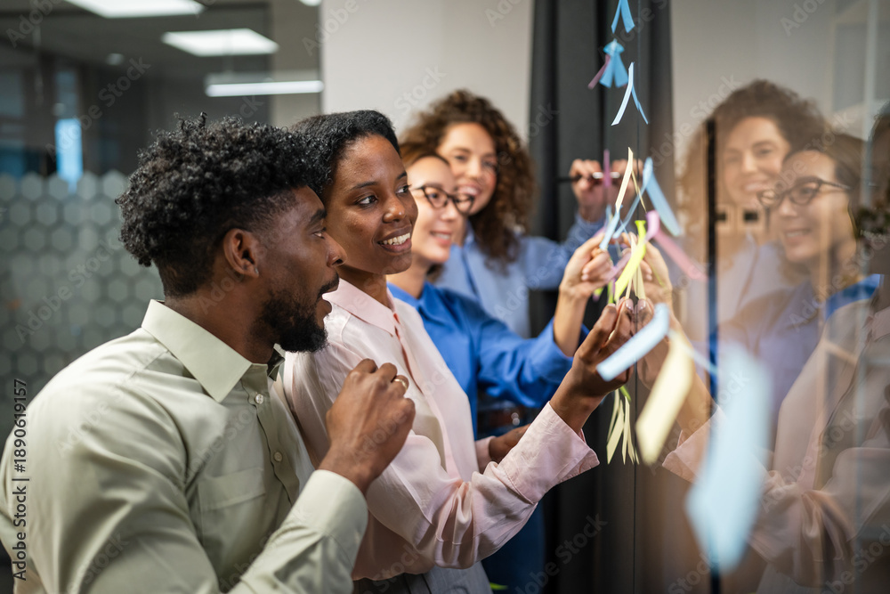 Obraz premium Diverse business team collaborating on glass board with sticky notes