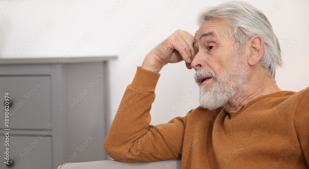Fototapeta premium Amnesia. Senior man trying to remember something at home, space for text