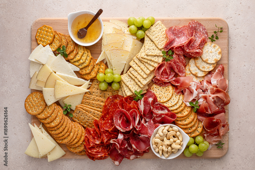 Fototapeta premium Charcuterie and cheese board with variety of meat and cheeses, crackers and nuts