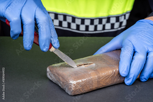 Close-up of a police officer’s hands opening a drug package.