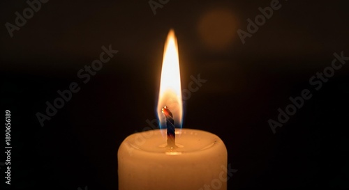 Close-up of a single candle flame burning brightly in a dark, peaceful environment, casting a warm glow