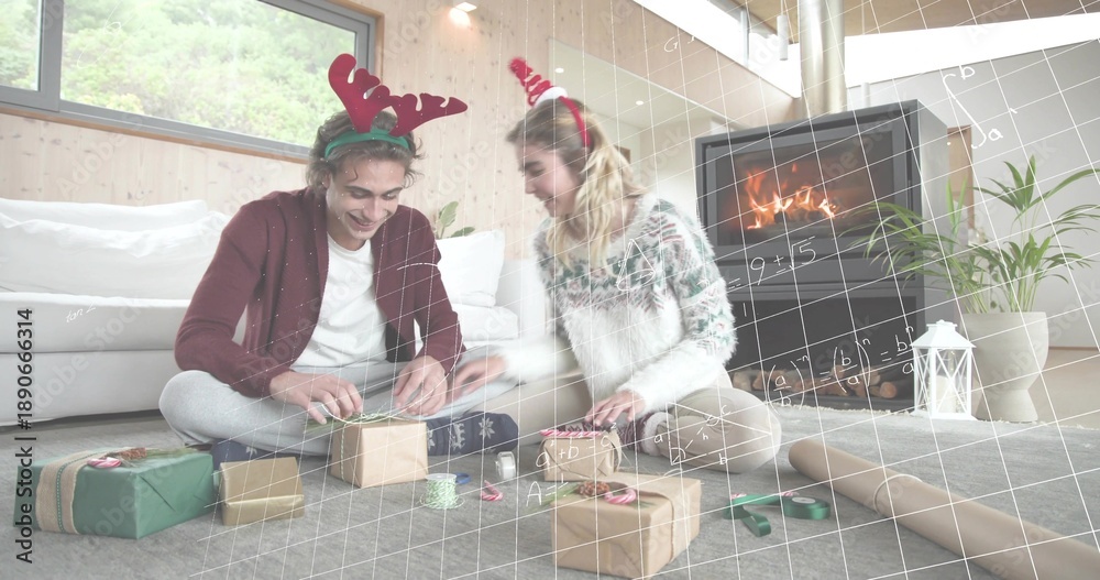 Fototapeta premium Wrapping friends wearing festive headbands and knits on living room floor, with gifts and ribbon
