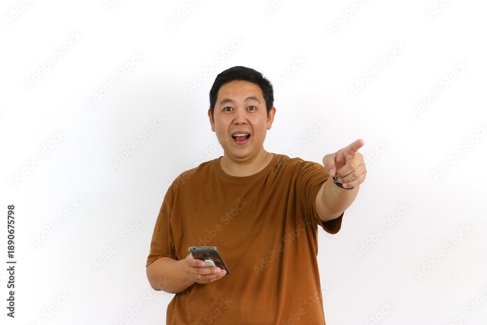 Fototapeta premium An Asian male individual reacting with a winning gesture and excited facial expression while using a smartphone.