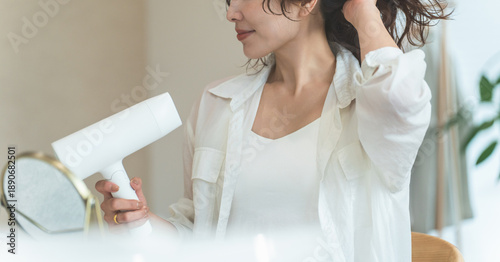 Cuadro en lienzo A woman blow-drying her hair with a hair dryer (hair care)