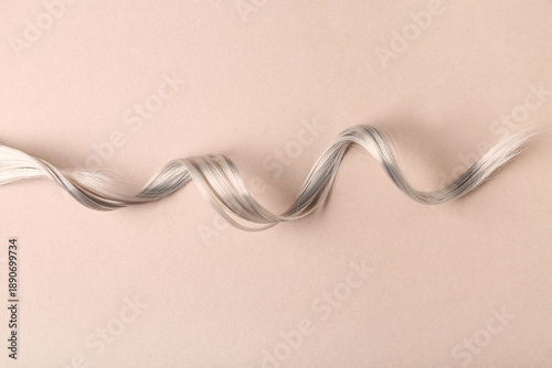 Foto Curly grey hair strand on brown background