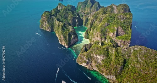 Aerial panorama of tropical Phi Phi Leh island with stunning limestone cliffs, lush green vegetation, and crystal clear turquoise waters in Maya Bay with longtail boats navigating the shallow lagoon