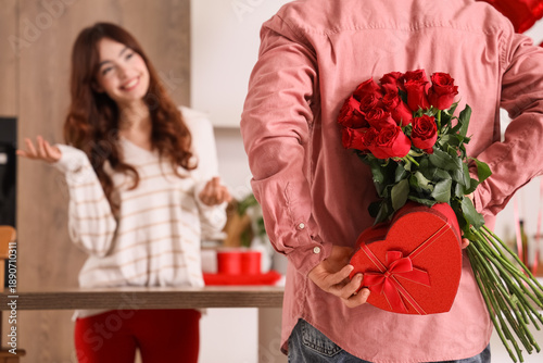 Young man hiding bouquet of...
