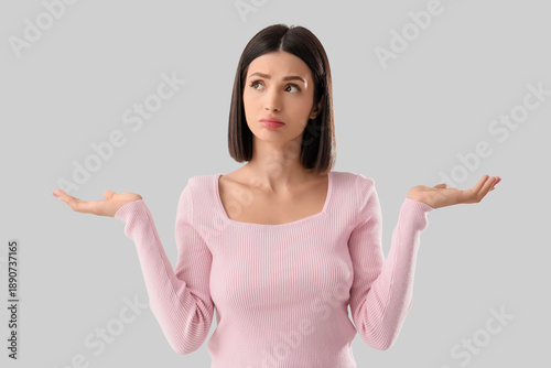 Thoughtful young woman on light background
