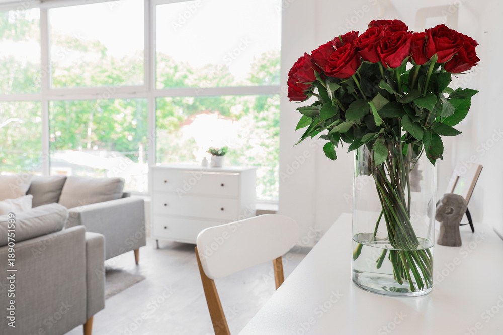 Fototapeta premium Vase with beautiful red roses on table in stylish living room